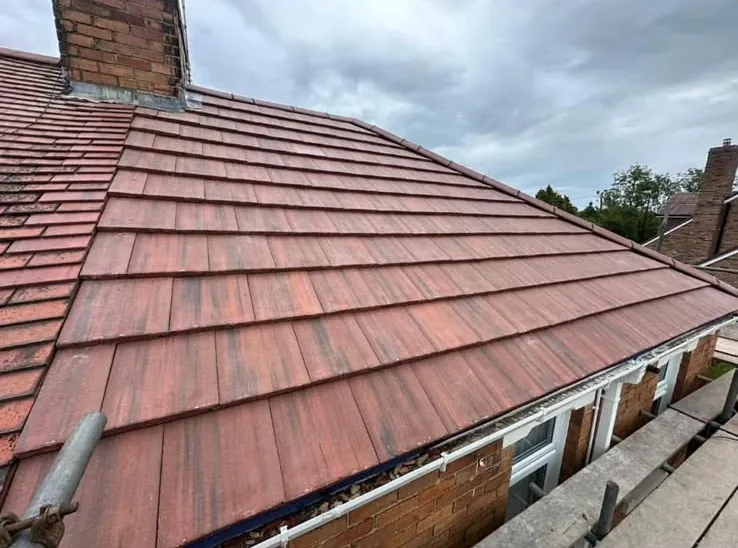 New pitched roof in red plain tiles with fresh ridge line and guttering