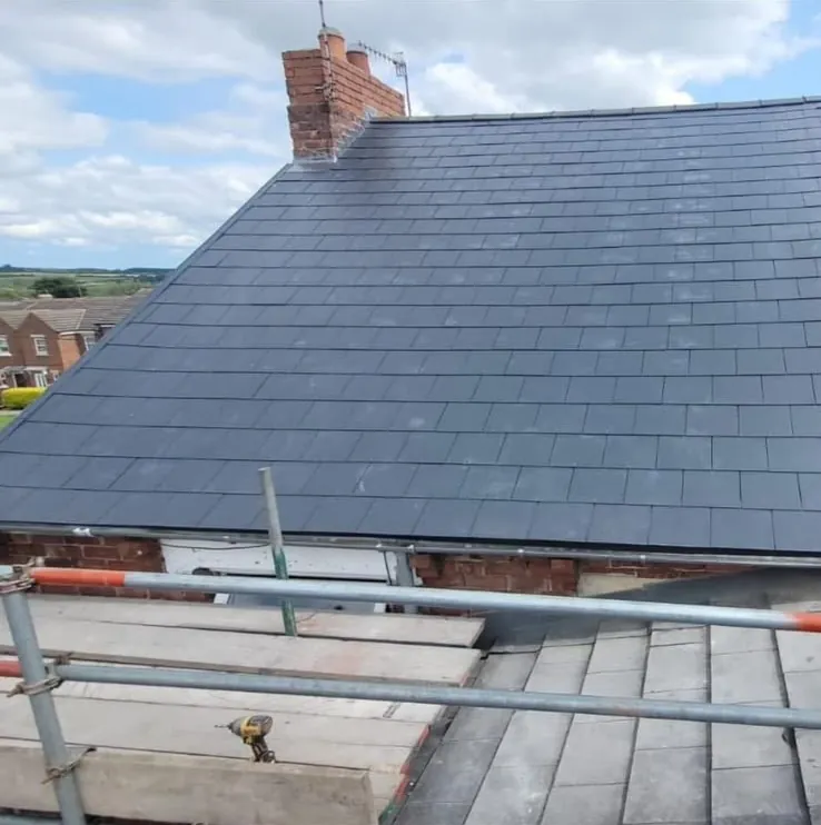 New slate pitched roof with lead flashing around a brick chimney